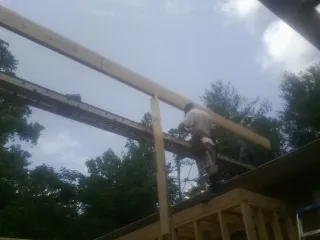 Carpenter setting a ridge beam over a new addition frame — Ice Dam Removal by Roofing Brothers in Charlotte